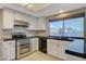 Well-lit kitchen showcasing stainless steel appliances, white cabinetry, and a garden view at 1800 Summit Pointe Dr, Las Vegas, NV 89117