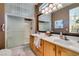 Main bathroom with double sinks, wood cabinets, a large mirror, and walk-in shower at 1811 Tiger Creek Ave, Henderson, NV 89012