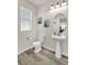 Well-lit half bathroom featuring sleek fixtures, a pedestal sink, and wood-look flooring at 225 Priority Point St, Henderson, NV 89012