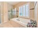 The main bathroom includes a large soaking tub, glass enclosed shower, and a window with shutters at 2375 Malaga Peak St, Las Vegas, NV 89135