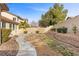 A large backyard featuring a concrete path, retaining wall, and various foliage at 283 Parisian Springs Ct, Las Vegas, NV 89148