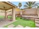 Landscaped backyard with a covered patio, artificial grass, a dining set, and multi-tiered retaining walls at 3021 Scenic Valley Way, Henderson, NV 89052