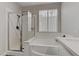 Modern bathroom showcasing a glass-enclosed shower, soaking tub, and bright natural light through the window at 3021 Scenic Valley Way, Henderson, NV 89052