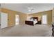 Large bedroom with beige carpet, ceiling fan, and a wooden bed frame with views into attached bathroom at 3741 Lily Haven Ave, Las Vegas, NV 89120