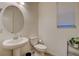 Bright powder room featuring a pedestal sink, toilet, and window with blinds at 4115 Spring Storm Ave, North Las Vegas, NV 89081