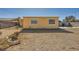 View of backyard with a wood fence, gravel and weeds for ground cover and two windows in the back of the house at 6120 Cairo Cir, Las Vegas, NV 89107