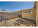 A fenced backyard with a block wall, some shrubbery, and a tan one story home, with clear blue skies at 6120 Cairo Cir, Las Vegas, NV 89107