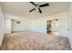 Spacious living room featuring neutral carpet, white walls, ceiling fan, and an open doorway to the kitchen at 6120 Cairo Cir, Las Vegas, NV 89107