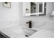 Modern bathroom with a marble countertop, sleek faucet, and illuminated mirror with doorway in the background at 6505 Moon Roses Ct, Las Vegas, NV 89108