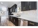 Modern kitchen features dark cabinetry, stainless steel appliances, and a bright white backsplash at 6505 Moon Roses Ct, Las Vegas, NV 89108