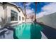 A lovely in-ground backyard pool is surrounded by palm trees and tall walls at 6505 Moon Roses Ct, Las Vegas, NV 89108