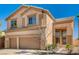 Two-story tan home featuring a two car garage, tile roof, and manicured landscaping at 74 Harbor Coast St, Las Vegas, NV 89148