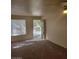 An apartment living room with an open doorway and a large window bringing natural light to a carpeted space at 7730 Secret Shore Dr # 207, Las Vegas, NV 89128