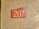 Close-up of Unit 207's numbering, mounted on a textured surface at 7730 Secret Shore Dr # 207, Las Vegas, NV 89128