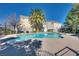 A community pool with clear water, palm trees and residential buildings surrounded by a black metal fence at 7978 Light Tower St, Las Vegas, NV 89139