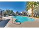 A community pool with clear blue water, surrounded by palm trees and residential buildings at 7978 Light Tower St, Las Vegas, NV 89139