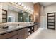 Bathroom with double vanity, marble countertops, a large mirror, and a decorative light fixture at 9 Stonecutter Ct, Henderson, NV 89012