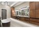 Elegant bathroom features freestanding tub, lots of wood cabinetry, and contemporary lighting at 9 Stonecutter Ct, Henderson, NV 89012