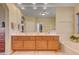 Bright bathroom with double vanity, wood cabinets, large mirror, and tub at 917 Collingtree St, Las Vegas, NV 89145