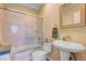 Well-lit bathroom featuring a shower-tub combo with glass doors and pedestal sink at 917 Collingtree St, Las Vegas, NV 89145