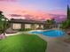 Beautiful backyard with a pool, lush lawn, lounge furniture, and an outdoor dining area under sunset skies at 11504 White Cliffs Ave, Las Vegas, NV 89138