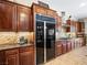 Well lit kitchen featuring custom wood cabinetry, stone backsplash, and black stainless steel refrigerator at 11504 White Cliffs Ave, Las Vegas, NV 89138