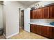 Neat laundry room features upper and lower dark wood cabinetry and tiled floor at 11504 White Cliffs Ave, Las Vegas, NV 89138