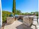 A full outdoor kitchen boasts stone accents, a built-in grill, sink, and counter seating for a luxurious backyard experience at 11504 White Cliffs Ave, Las Vegas, NV 89138