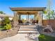 Covered patio with stone columns provides a shaded outdoor seating area with a ceiling fan and desert landscaping at 11504 White Cliffs Ave, Las Vegas, NV 89138