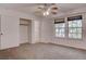 Bright bedroom features neutral carpet, ceiling fan with light fixture, and windows overlooking backyard at 1584 Bermuda Dunes Dr, Boulder City, NV 89005