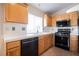 Bright kitchen with an island, wood cabinets, and modern black appliances on an easy-to-clean tile floor at 204 Mchenry St, Las Vegas, NV 89144