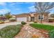 Inviting home showcasing a stone facade, a two-car garage, desert landscaping, and a small patch of green lawn at 2535 Jada Dr, Henderson, NV 89044