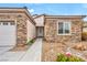 Close-up of a home's facade featuring stone accents, a front door with an oval glass pane, and desert landscaping at 2535 Jada Dr, Henderson, NV 89044