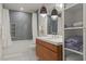 Bright bathroom with tub, tiled walls, modern vanity, pendant lights, and open linen shelving at 3452 Spanish Winds Ct, Las Vegas, NV 89141
