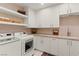 Functional laundry room with white cabinetry, countertops, open shelves, and modern washer and dryer at 3452 Spanish Winds Ct, Las Vegas, NV 89141