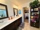 This bathroom has dual sinks, dark cabinets, framed mirrors and an entrance to the walk-in closet at 384 Gracious Way, Henderson, NV 89011