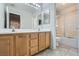 Bright bathroom featuring double sinks with wood cabinets and a shower-tub combo with sliding glass doors at 3925 Champagne Wood Dr, North Las Vegas, NV 89031