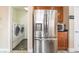 Kitchen features stainless steel refrigerator, laundry room, microwave and wooden cabinets at 63 Crescent Palm Ct, Henderson, NV 89002