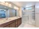 Bright bathroom featuring a double sink vanity, large mirror and glass-enclosed shower at 6637 Rockhouse St, North Las Vegas, NV 89086