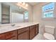 Bright bathroom with a large mirror over a vanity with dark wood cabinets and white countertop, next to a toilet at 6637 Rockhouse St, North Las Vegas, NV 89086