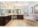 Elegant bathroom featuring dual sinks, a vanity area, a soaking tub and warm tones at 837 Roseberry Dr, Las Vegas, NV 89138