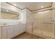 Bright bathroom featuring double sinks, lighted mirror, white cabinets, and a glass-enclosed shower at 8446 Vacarez Dr, Las Vegas, NV 89149