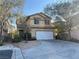 Tan two-story home with a two car garage and desert landscaping at 9299 Adamshurst Ave, Las Vegas, NV 89148