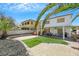 The backyard is ideal for recreation and leisure with a covered patio, manicured greenery, and mature palms at 10218 Maltese Cross Ct, Las Vegas, NV 89183