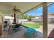 Wonderful covered patio with a grill, dining table, artificial turf, and palm trees enhance backyard enjoyment at 10218 Maltese Cross Ct, Las Vegas, NV 89183