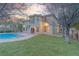 Backyard at dusk with swimming pool, mature trees, and covered patio at 11002 Inverlochy Ct, Las Vegas, NV 89141