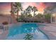 Beautiful pool area with mature landscaping, a brick privacy wall, and colorful sunset sky at 11002 Inverlochy Ct, Las Vegas, NV 89141