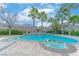 Beautiful pool features a built in spa and tropical landscaping with mature palm trees and blue skies at 11002 Inverlochy Ct, Las Vegas, NV 89141