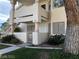 Exterior view of a two story home with a stucco finish, metal gate, and desert landscaping at 1105 Sulphur Springs Ln # 102, Las Vegas, NV 89128