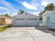 Detached two-car garage with white doors, surrounded by a spacious concrete driveway and manicured greenery at 1139 5Th Pl, Las Vegas, NV 89104